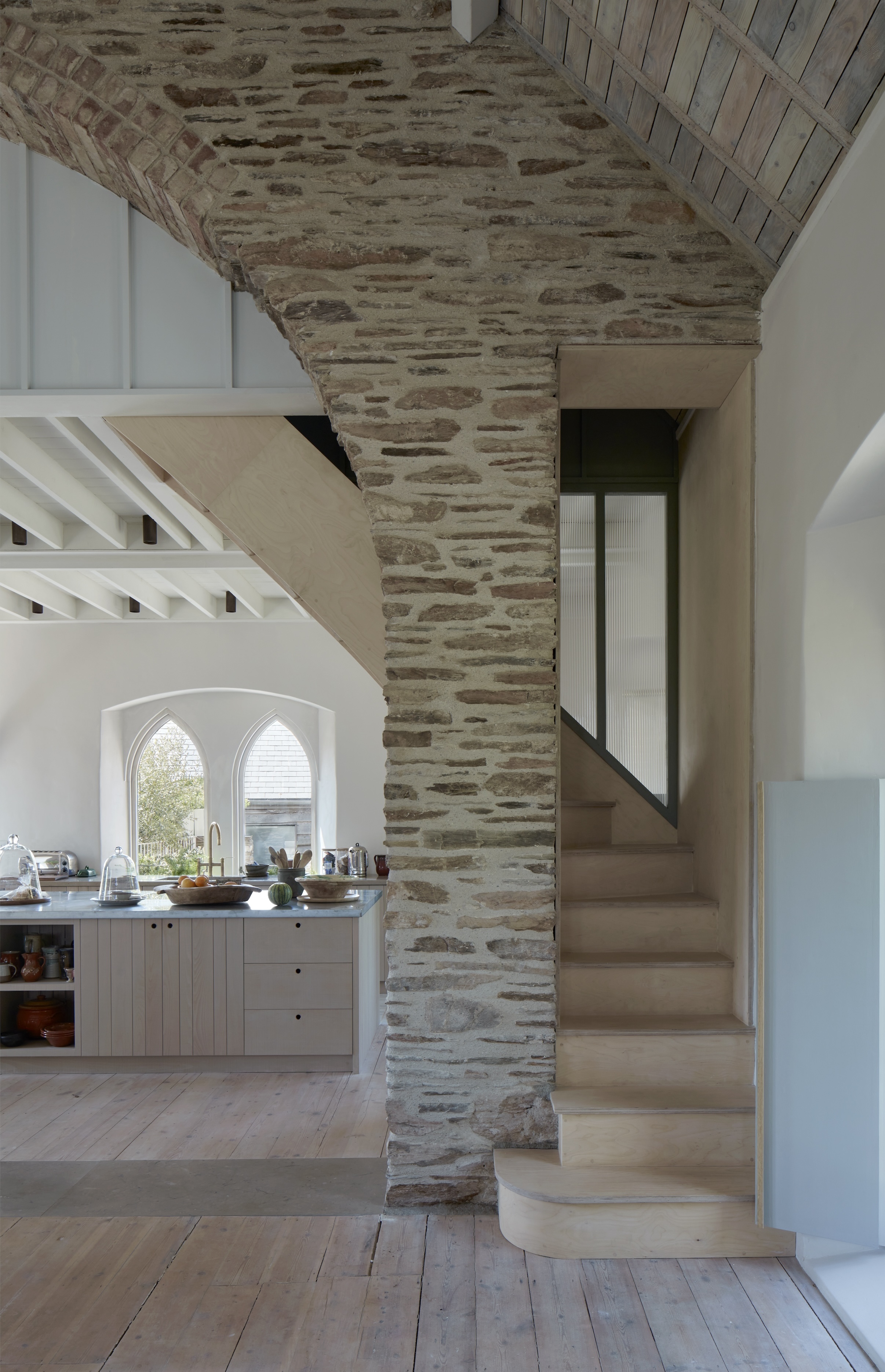 the architects tucked a mezzanine over the kitchen. the plywood staircase with  26