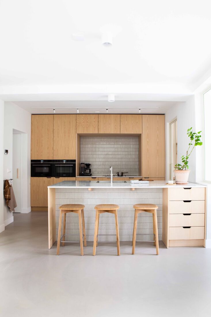 the kitchen is fitted with custom cabinets of ash offset by linear suisai tiles 17