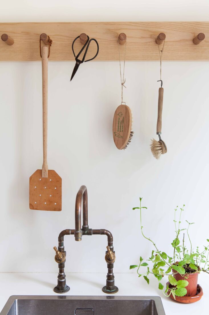 a peg rail holds utility tools over the laundry sink with a plumber made copper 23