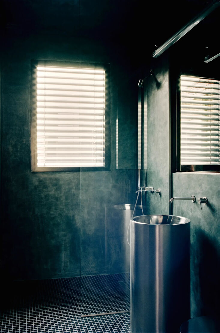 the adjoining bath is finished with dark blue tadelakt walls and black mosaic t 26